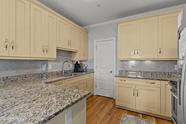 kitchen featuring gas range, stone counters, sink, backsplash, and light hardwood / wood-style floors