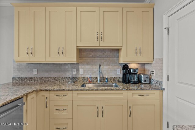 kitchen featuring light stone countertops, decorative backsplash, dishwasher, and sink