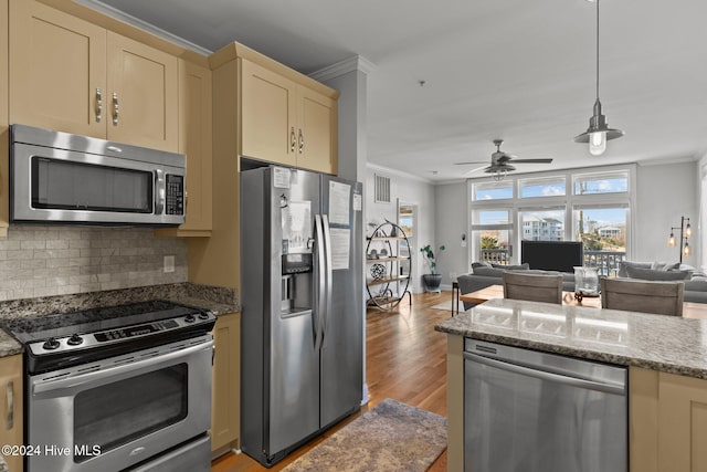 kitchen featuring light stone countertops, backsplash, ornamental molding, stainless steel appliances, and light hardwood / wood-style floors