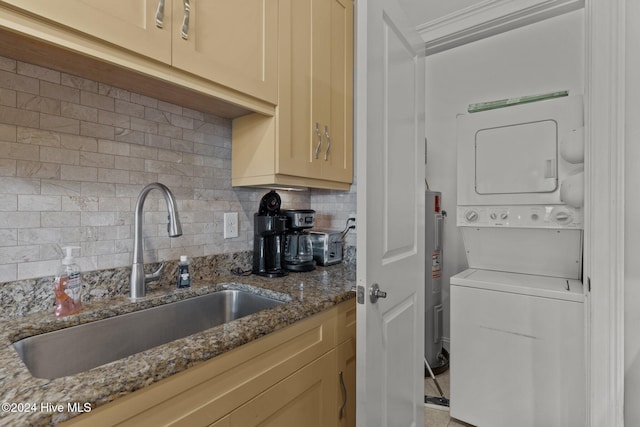 kitchen with decorative backsplash, electric water heater, sink, stone countertops, and stacked washer and dryer