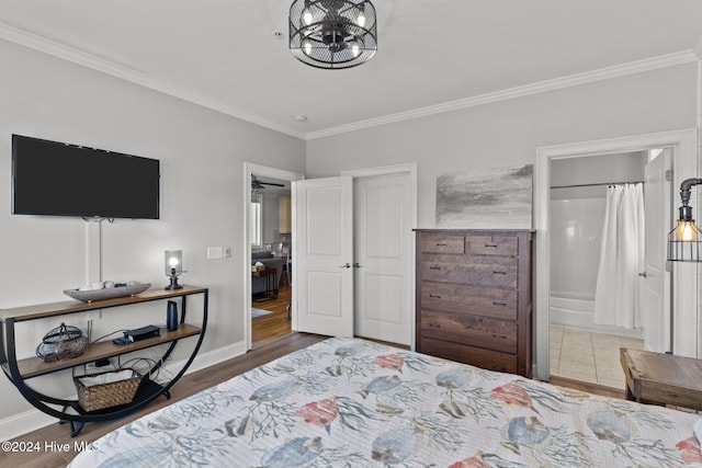 bedroom with wood-type flooring, crown molding, and connected bathroom