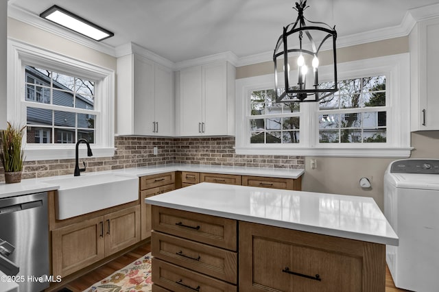 kitchen with washer / dryer, a sink, light countertops, stainless steel dishwasher, and tasteful backsplash