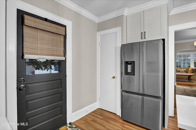 kitchen with light wood-type flooring, baseboards, stainless steel fridge with ice dispenser, and crown molding