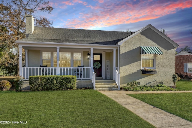 bungalow-style home with covered porch and a yard