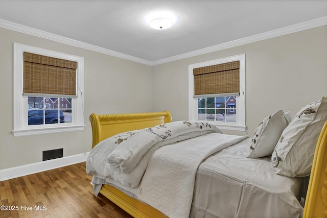 bedroom with visible vents, ornamental molding, and wood finished floors