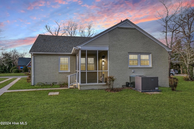 exterior space featuring brick siding, central AC unit, a yard, a sunroom, and crawl space