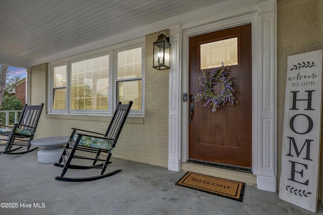 doorway to property with brick siding and covered porch