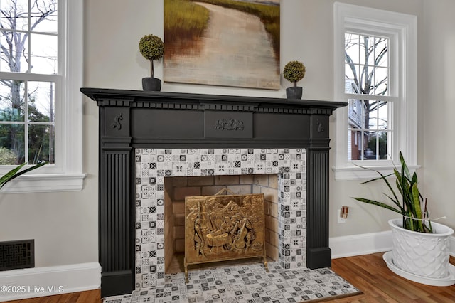 details featuring visible vents, baseboards, wood finished floors, and a fireplace