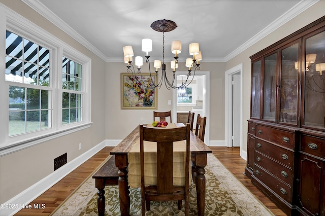 dining space featuring dark wood-style floors, baseboards, crown molding, and an inviting chandelier