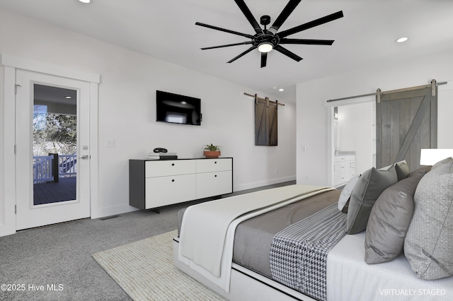 bedroom with a barn door, connected bathroom, light colored carpet, and ceiling fan