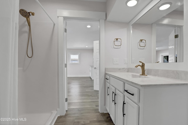 bathroom with hardwood / wood-style flooring, vanity, and walk in shower