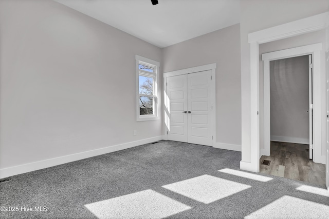 unfurnished bedroom featuring ceiling fan, a closet, and dark colored carpet