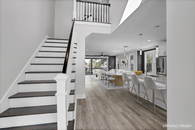 stairs with a high ceiling, sink, hardwood / wood-style floors, and ceiling fan