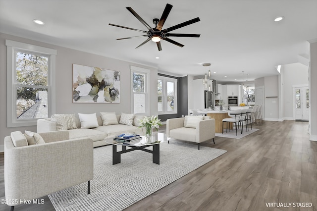 living room featuring ceiling fan, light wood-type flooring, and a wealth of natural light