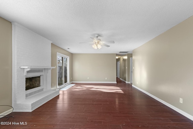 unfurnished living room featuring a brick fireplace, ceiling fan, visible vents, and dark wood-style flooring