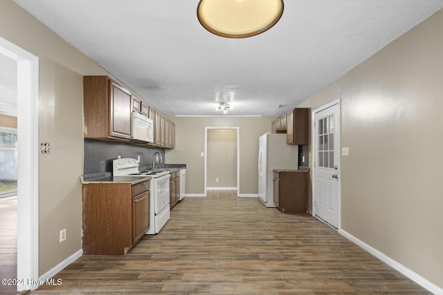 kitchen with a textured ceiling, dark hardwood / wood-style flooring, white appliances, and sink