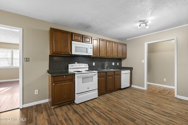 kitchen featuring dark hardwood / wood-style floors, decorative backsplash, white appliances, and a textured ceiling