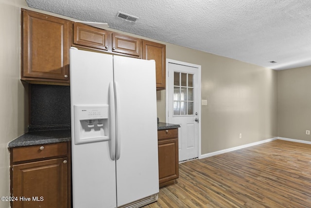 kitchen featuring a textured ceiling, wood-type flooring, and white refrigerator with ice dispenser