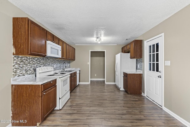 kitchen featuring white appliances, dark wood-type flooring, a sink, light countertops, and tasteful backsplash