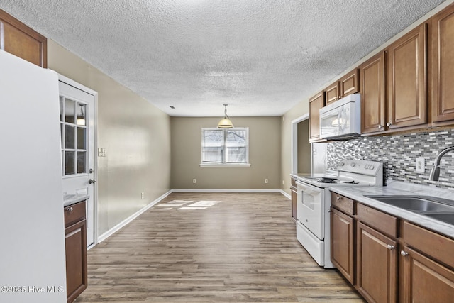 kitchen featuring light countertops, white appliances, and brown cabinetry