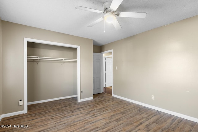 unfurnished bedroom with a textured ceiling, ceiling fan, a closet, and dark hardwood / wood-style floors