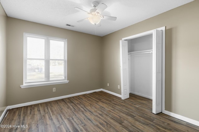 unfurnished bedroom featuring dark hardwood / wood-style flooring, a closet, multiple windows, and ceiling fan