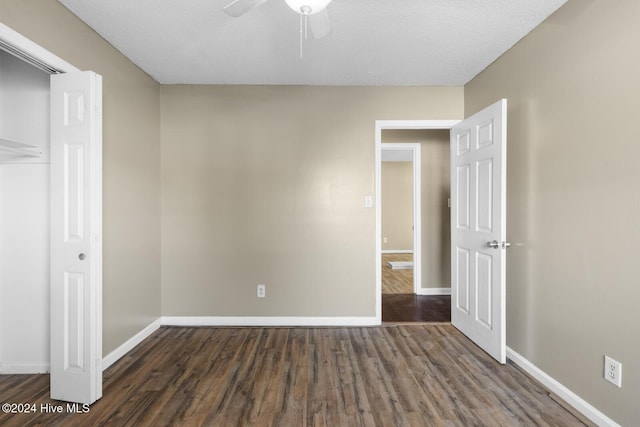 unfurnished bedroom with a textured ceiling, ceiling fan, and dark wood-type flooring