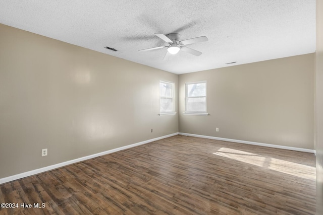 unfurnished room with dark wood-style floors, visible vents, ceiling fan, a textured ceiling, and baseboards