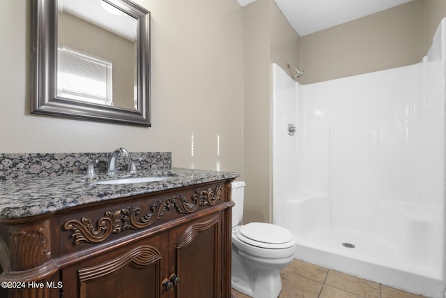 bathroom featuring tile patterned flooring, vanity, toilet, and walk in shower