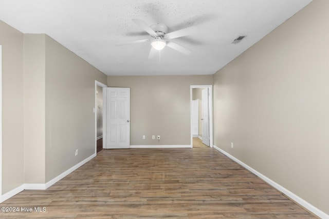 spare room with visible vents, ceiling fan, a textured ceiling, wood finished floors, and baseboards