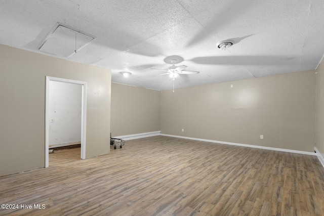 unfurnished room with attic access, a textured ceiling, baseboards, and wood finished floors