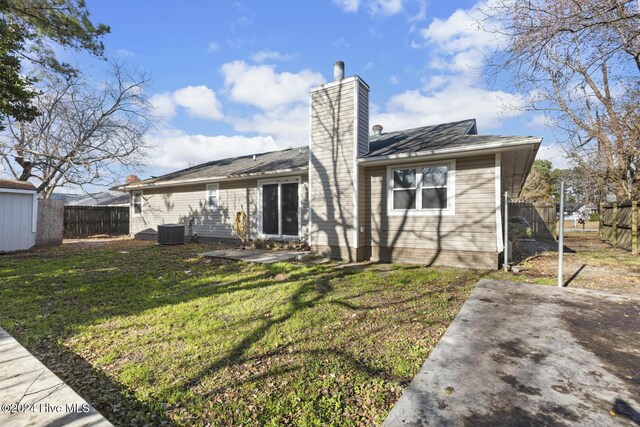 rear view of house featuring central AC unit, a lawn, a chimney, fence, and a patio area