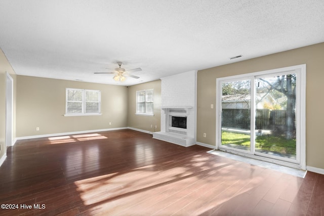 unfurnished living room featuring hardwood / wood-style flooring, a fireplace, ceiling fan, and a textured ceiling