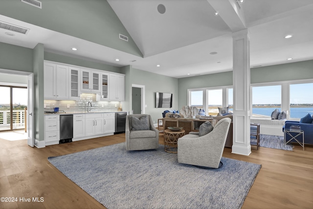 living room with light wood-type flooring, plenty of natural light, and decorative columns