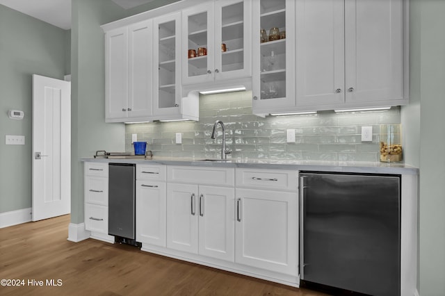 kitchen with dark hardwood / wood-style floors, backsplash, stainless steel refrigerator, white cabinets, and sink