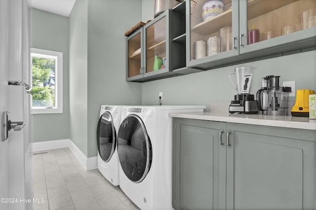 clothes washing area with separate washer and dryer and cabinets