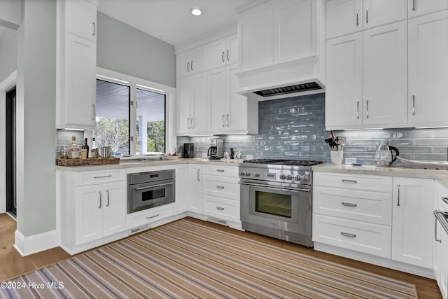 kitchen with decorative backsplash, white cabinets, and appliances with stainless steel finishes