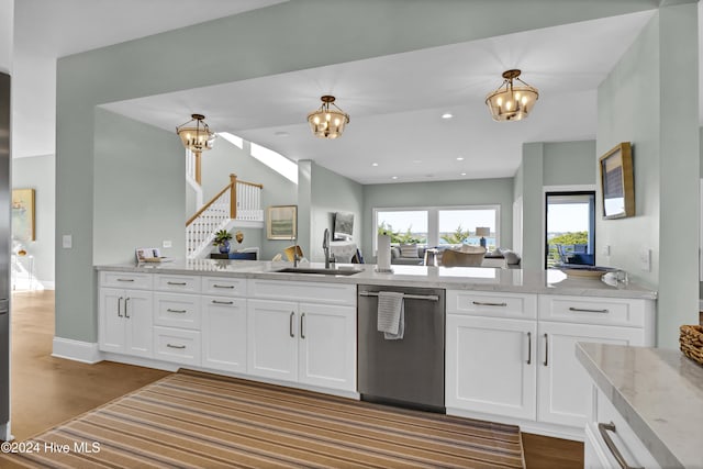 kitchen featuring decorative light fixtures, white cabinets, dishwasher, and sink