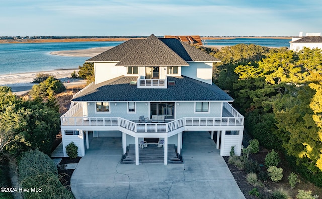 view of front of property with a water view, a carport, a balcony, and a beach view