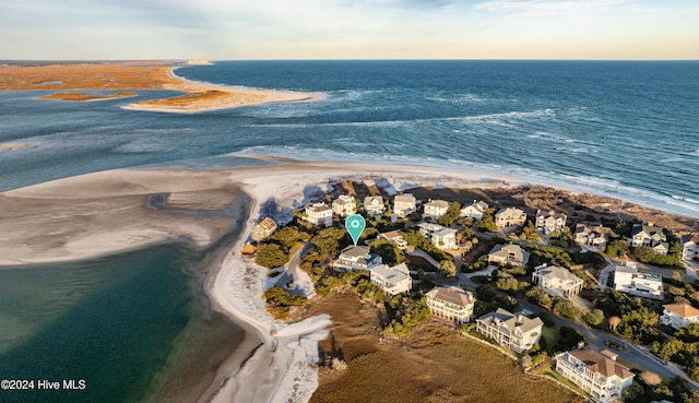 aerial view at dusk featuring a water view and a view of the beach