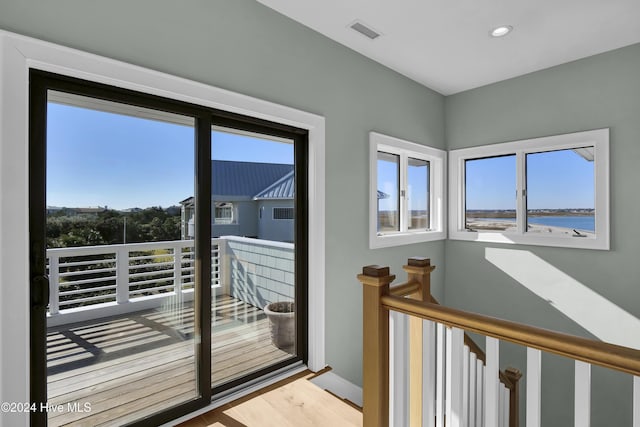 doorway with a water view and light hardwood / wood-style floors