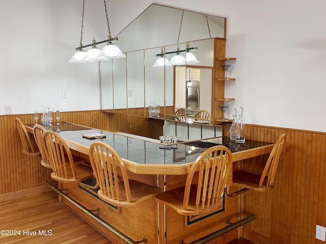 dining room featuring wood walls, light hardwood / wood-style flooring, and lofted ceiling