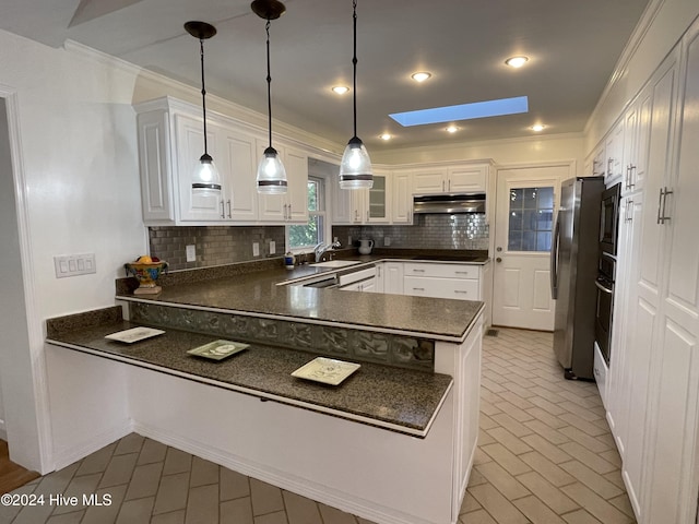 kitchen with kitchen peninsula, pendant lighting, a skylight, and white cabinetry