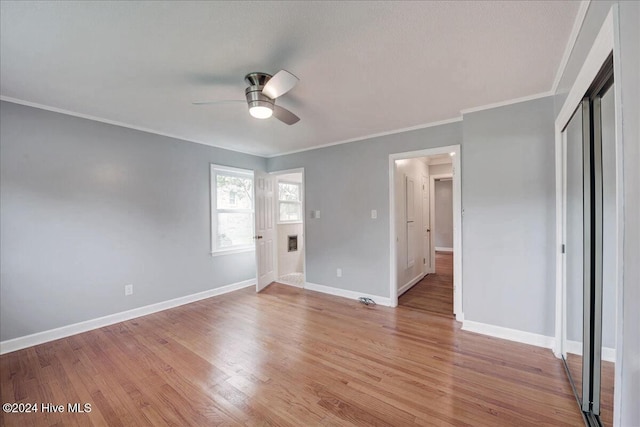 unfurnished bedroom with a closet, ceiling fan, crown molding, and light hardwood / wood-style floors