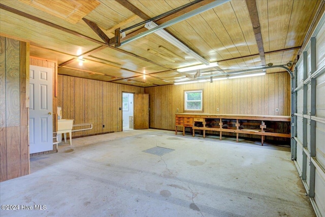 garage featuring a workshop area, wood walls, and wooden ceiling