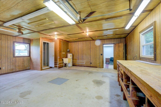 basement with a workshop area, a healthy amount of sunlight, wood walls, and wood ceiling