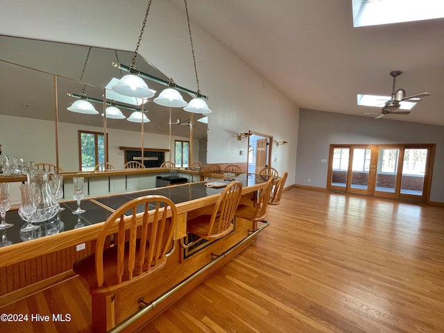 dining room with hardwood / wood-style floors, ceiling fan, and vaulted ceiling with skylight