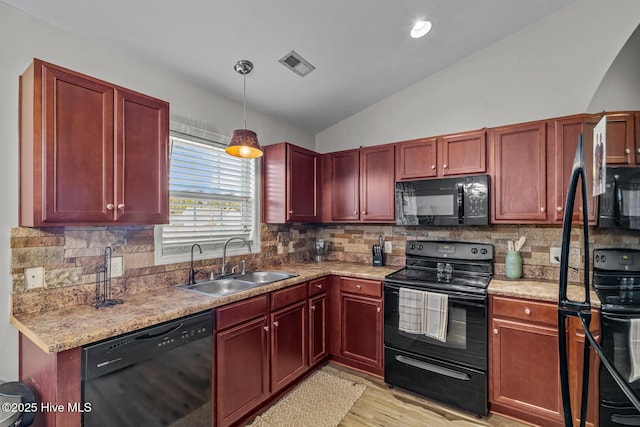 kitchen with light hardwood / wood-style flooring, sink, decorative light fixtures, black appliances, and lofted ceiling