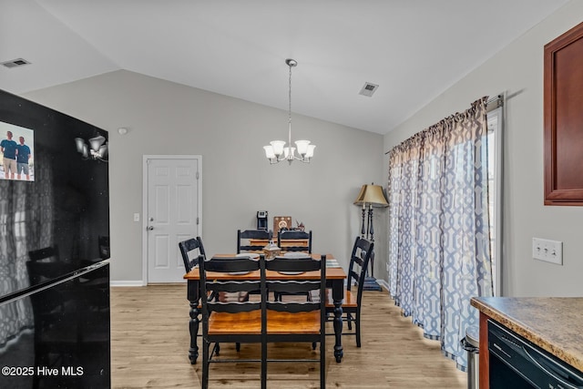 dining area with a chandelier, light hardwood / wood-style flooring, and lofted ceiling