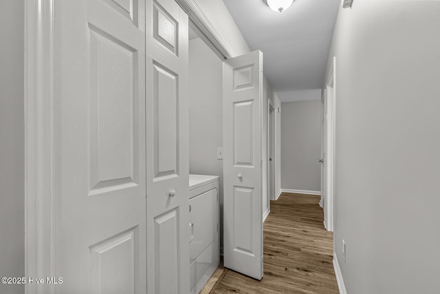 corridor with washer / clothes dryer and light hardwood / wood-style floors